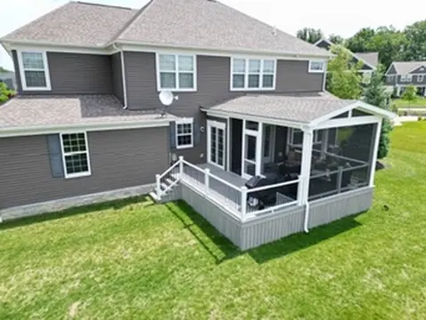 Two-level deck with white railing attached to gray house by DreamDecks