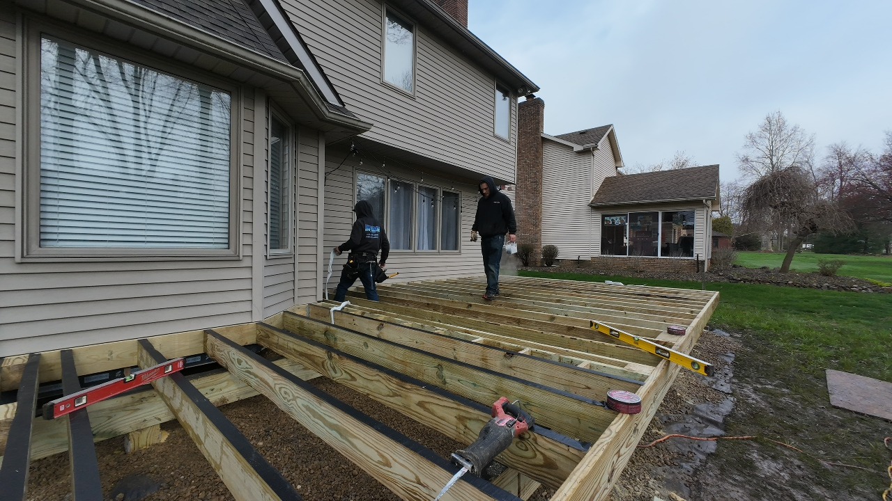 Two workers building a wooden framed deck with joists by DreamDecks in Northeast Ohio