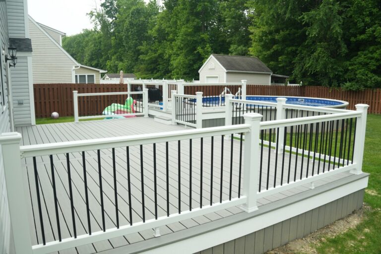 Gray composite wraparound deck with white railing next to an above ground pool, built by DreamDecks in Northeast Ohio