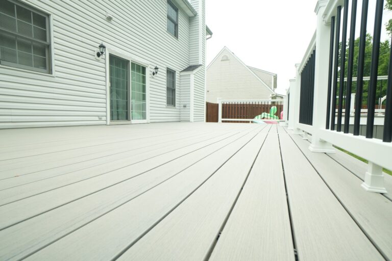 Gray composite wraparound deck with white railing next to an above ground pool, built by DreamDecks in Northeast Ohio
