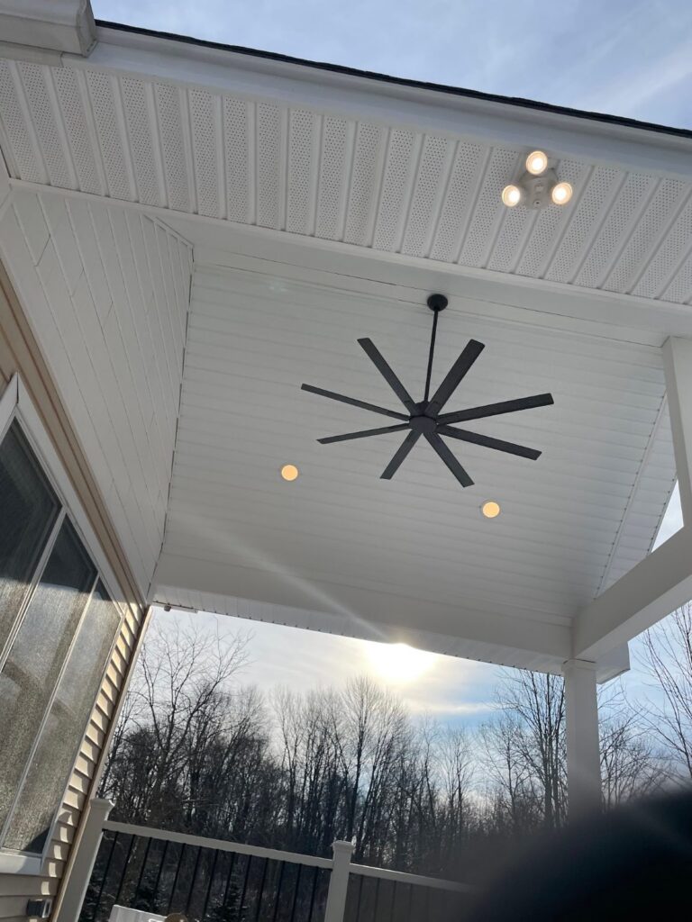Covered composite deck with a vaulted white ceiling, ceiling fan, and lights, built by DreamDecks in Hudson, Ohio