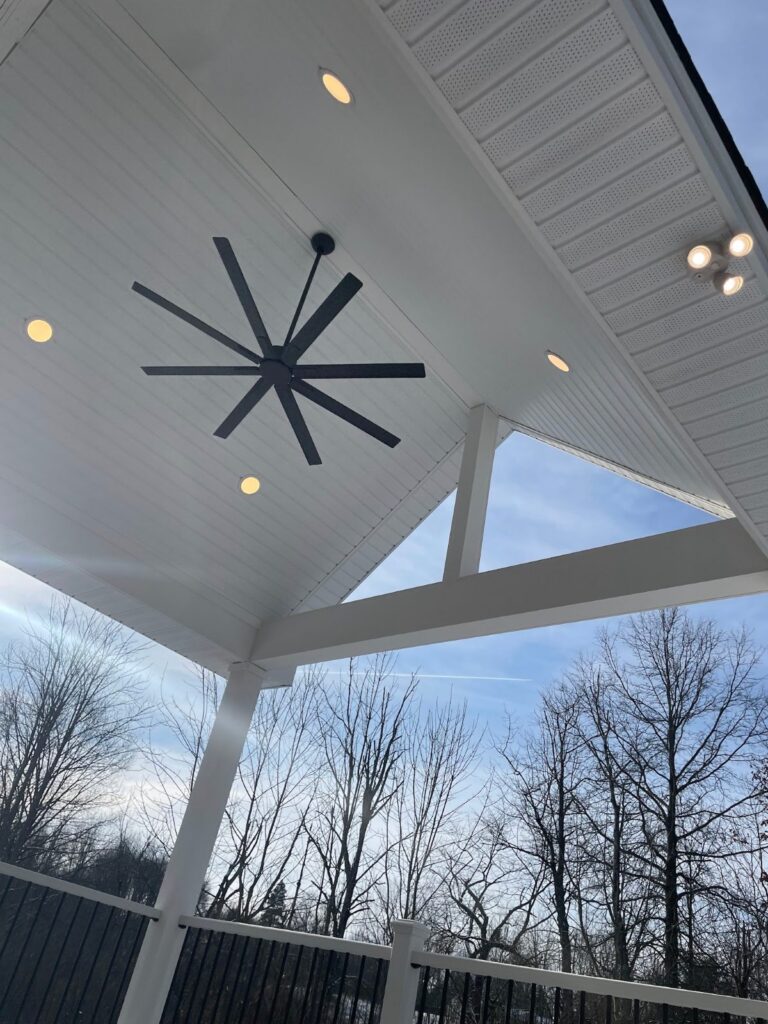 Covered composite deck with a vaulted white ceiling, ceiling fan, and lights, built by DreamDecks in Hudson, Ohio