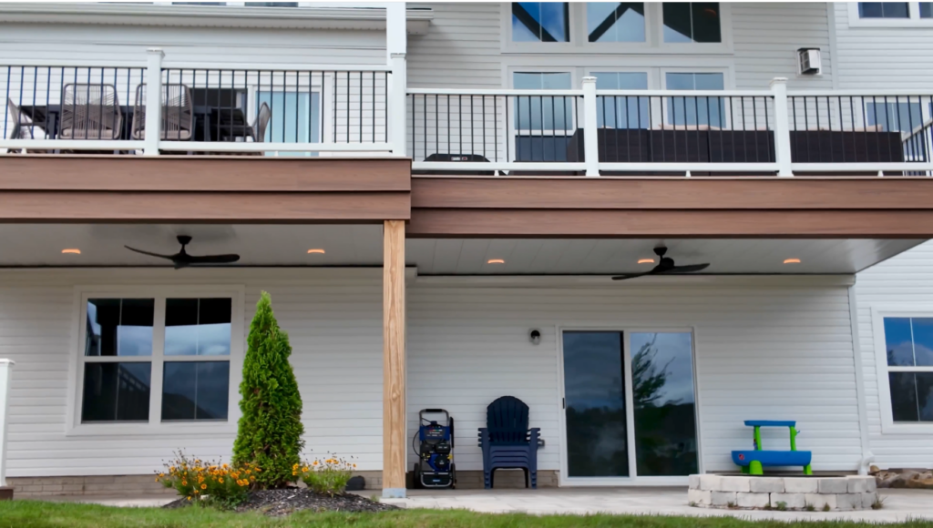 Two story Trex Lineage Carmel deck with Jasper fascia, white Trex Select railing, and a dry patio below with recessed lights and two ceiling fans in Richfield Ohio