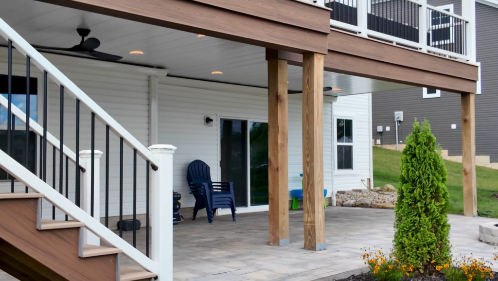 Trex Lineage stairs with white Trex Select railing next to the dry patio under the upper deck, with recessed lights and ceiling fans in Richfield Ohio