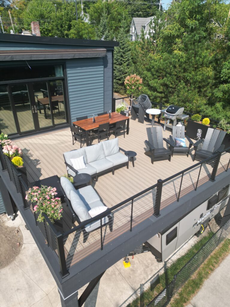 Elevated composite deck with black steel style posts, black cable railing and a covered space below on a modern building