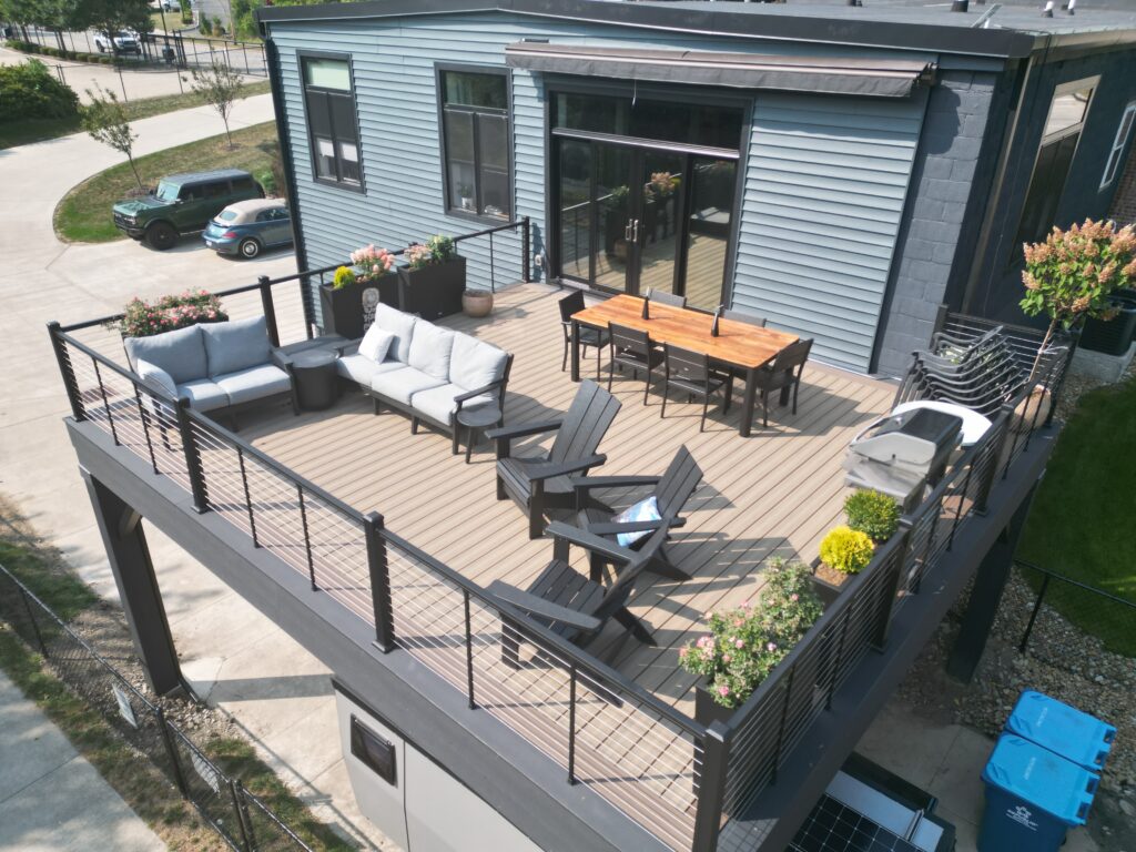 Elevated composite deck with black steel style posts, black cable railing and a covered space below on a modern building