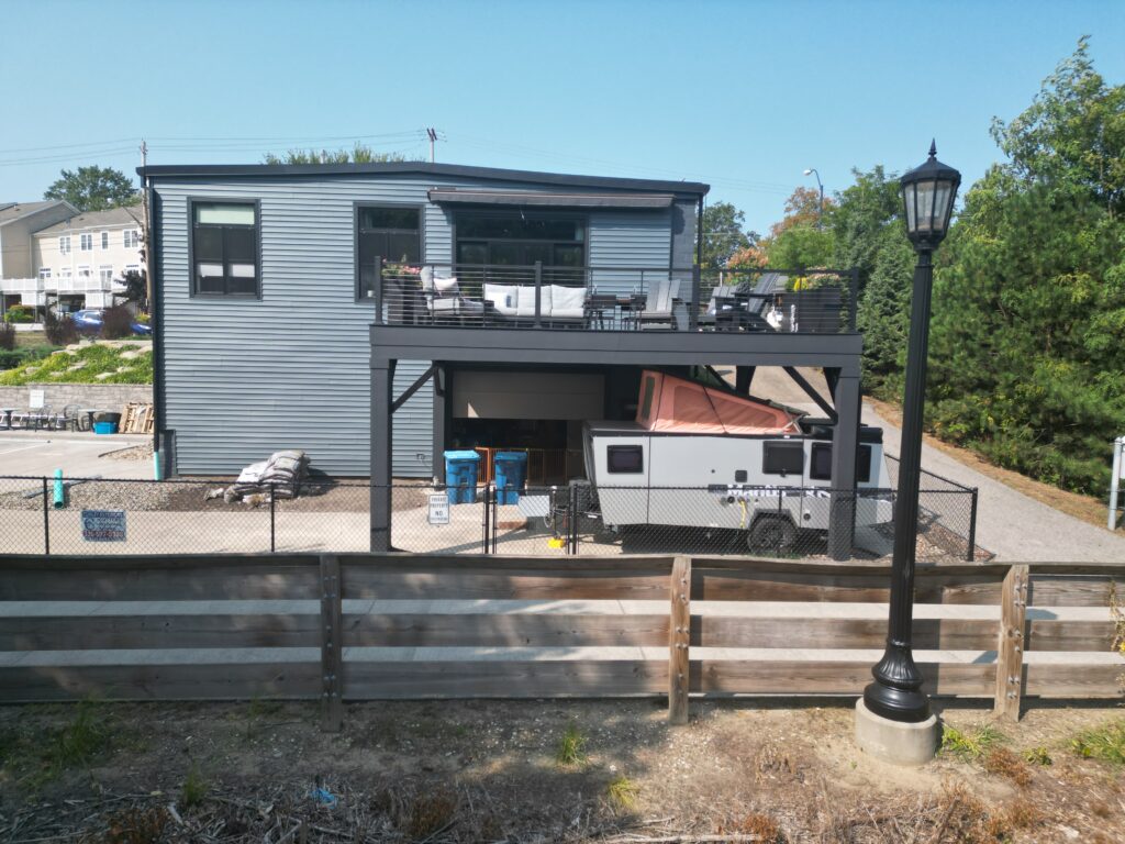 Elevated composite deck with black steel style posts, black cable railing and a covered space below on a modern building